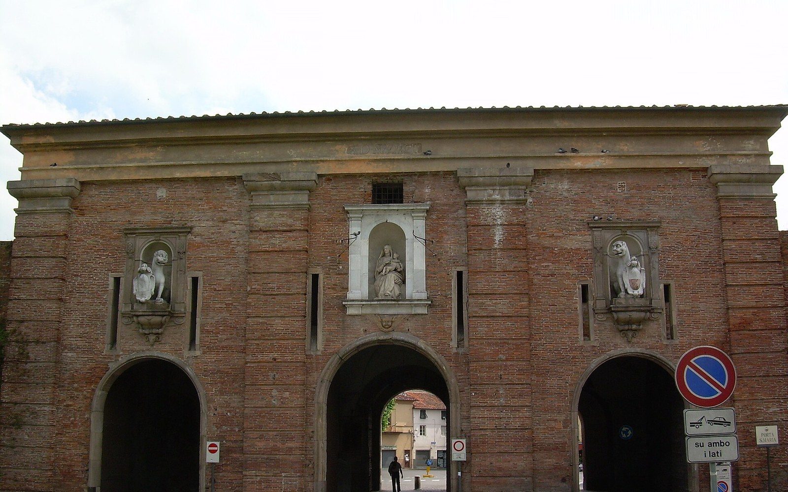 A brick town gate arch with a traffic-restriction plate bolted beside it